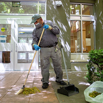 Staff member sweeping leaves outside